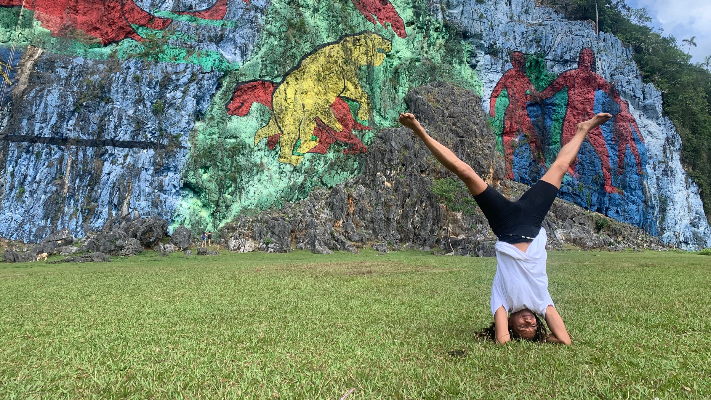 A person practicing yoga outdoors in front of a colorful mural